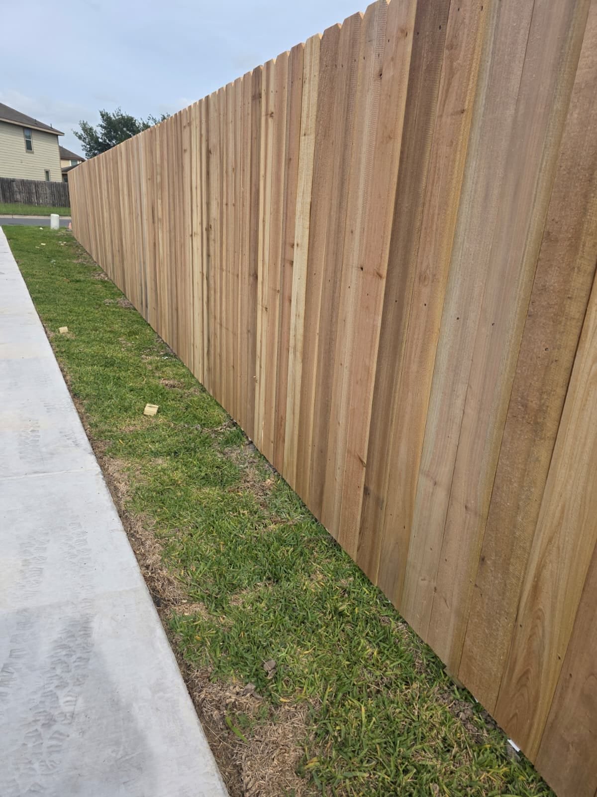 A finished wooden privacy fence running alongside a clean walkway